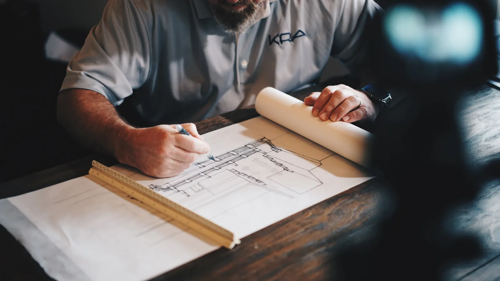 Architecte traçant un plan de maison à la règle sur une table de travail, préparation d'une demande d'autorisation de travaux au Maroc