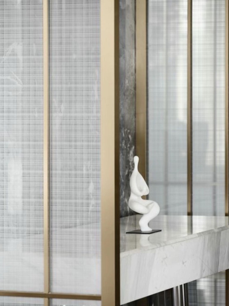 Détail de cloison en verre texturé doré sur marbre blanc avec sculpture décorative, finition luxe pour rénovation Agadir