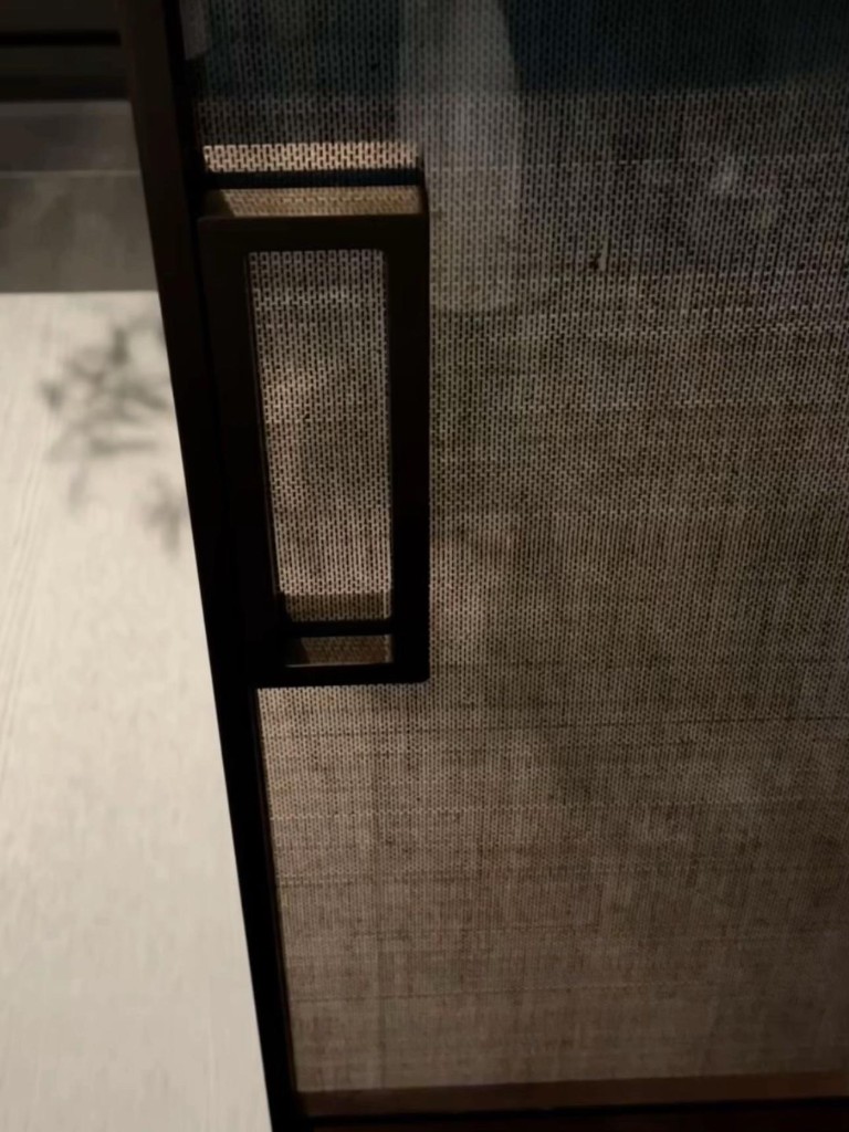 Porte en verre à maille texturée avec poignée verticale minimaliste en métal noir, détail design pour dressing ou bureau